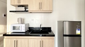 Una cucina moderna con mobili chiari in legno, un frigorifero in acciaio inox, un forno a microonde e una cucina a gas.