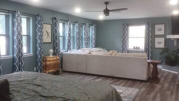 A bedroom with a bed, a sofa, a nightstand, and a ceiling fan.