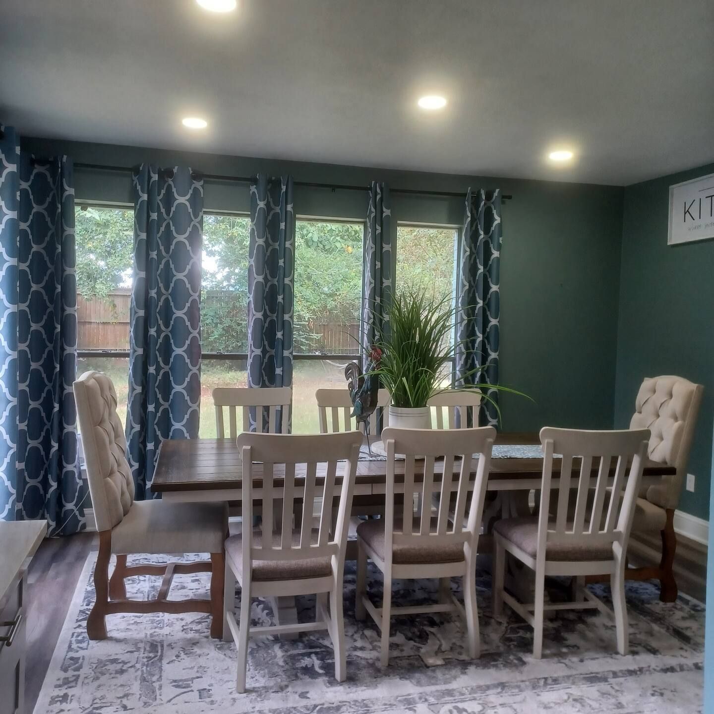 A dining area with a table and chairs, a potted plant, and a view of the outdoors.