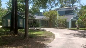 A residential property with a driveway leading to a house, surrounded by trees and a well-maintained lawn.
