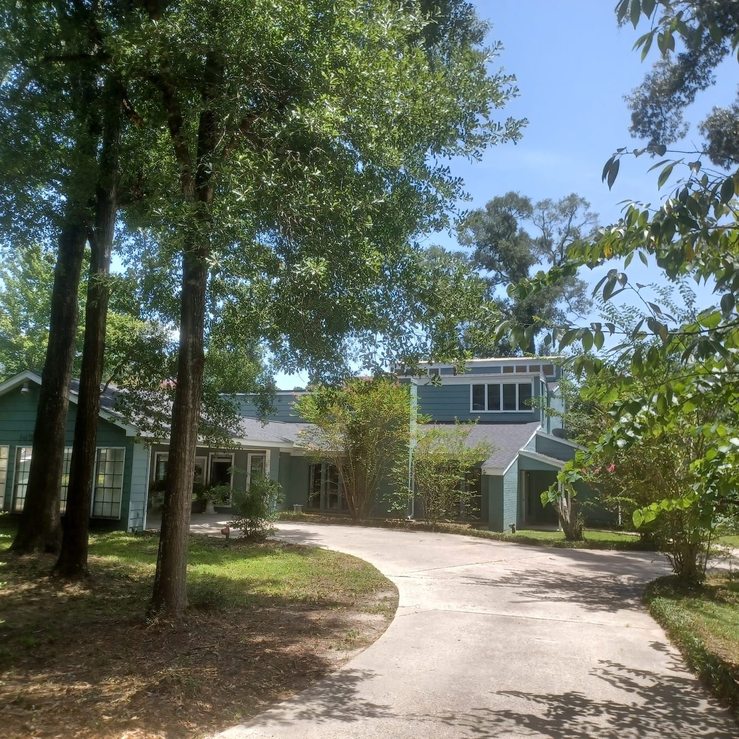 A residential area with a driveway leading to a house with a gabled roof and a front porch.