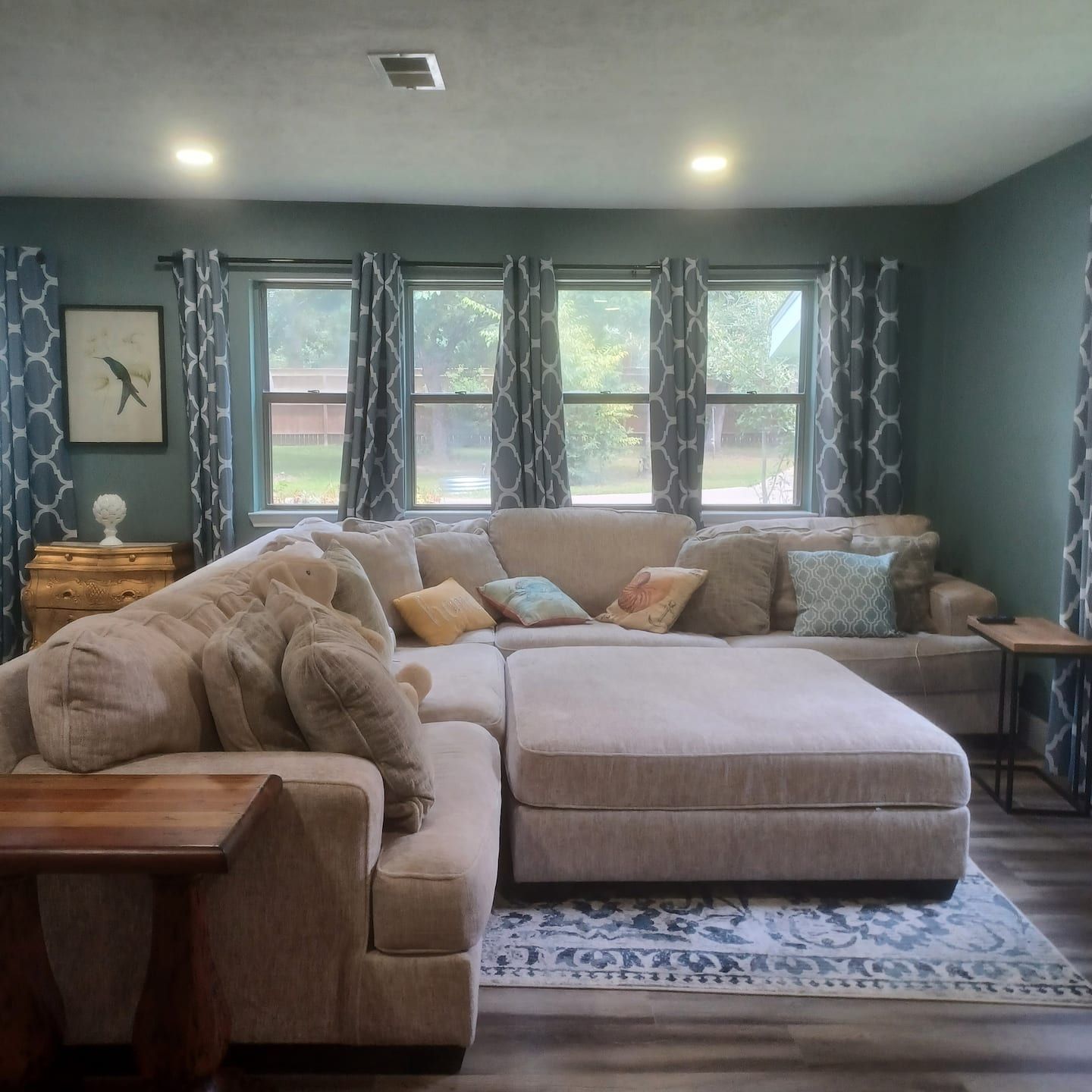 A living room with a sectional sofa, a wooden coffee table, and a patterned rug.