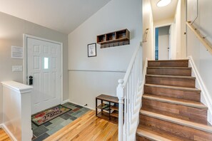 A staircase with wooden steps and white railings, leading to a landing with a small wooden shelf and a door. - The Buttonwood Retreat Game Room Fire Pit (Tobyhanna)
