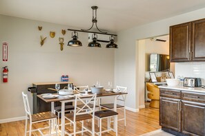 A dining area with a wooden table, white chairs, and a chandelier. - The Buttonwood Retreat Game Room Fire Pit (Tobyhanna)