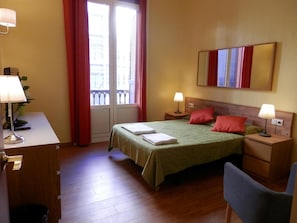 A hotel room with a bed, two bedside tables with lamps, a desk with a lamp, a chair, and a window with curtains. - Barcelona Central Garden (Barcelona)