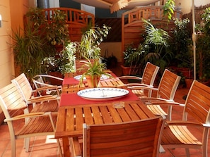An outdoor patio with wooden tables and chairs, surrounded by potted plants. - Barcelona Central Garden (Barcelona)