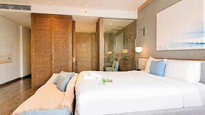 Quarto de hotel com cama, banheiro com chuveiro de vidro e armário de madeira.