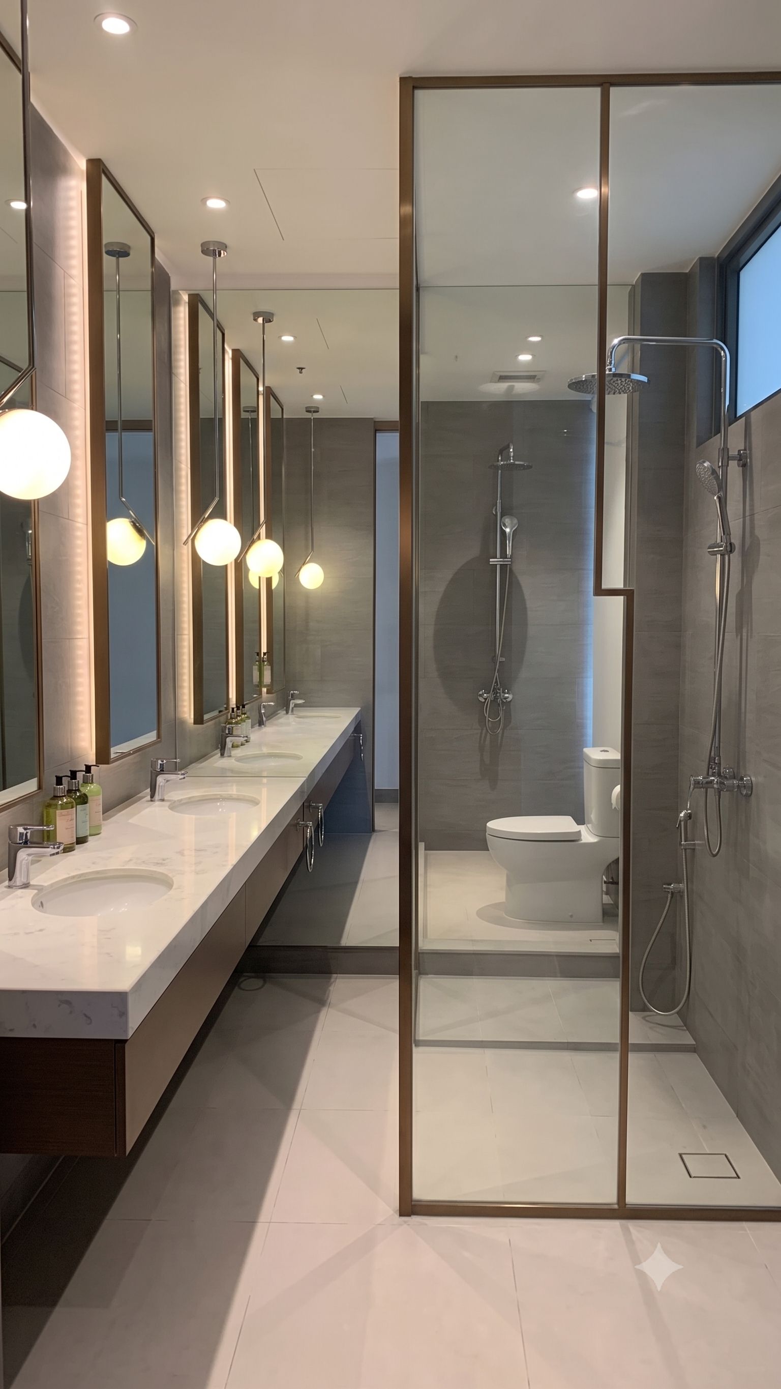 Un baño moderno con mampara de vidrio, dos lavamanos y zona de ducha.