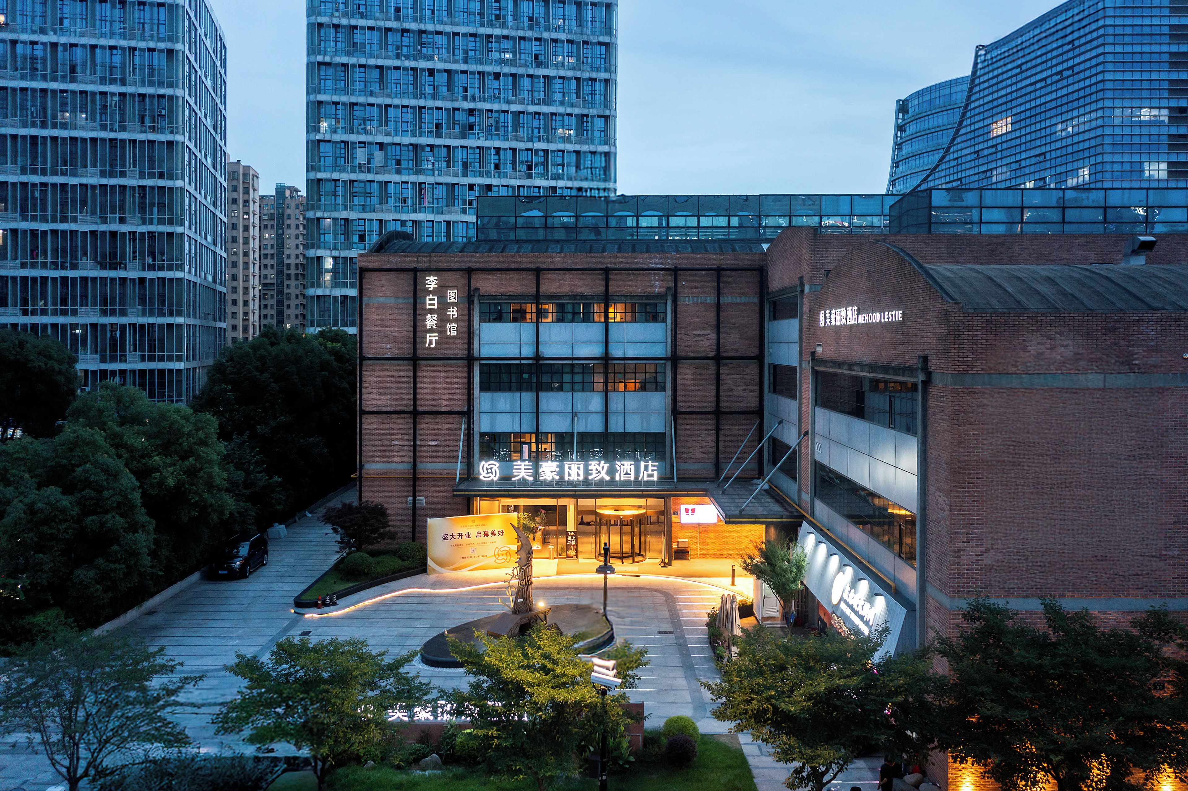 Un hotel amb façana de maó modern, finestres grans i una entrada ben il·luminada.
