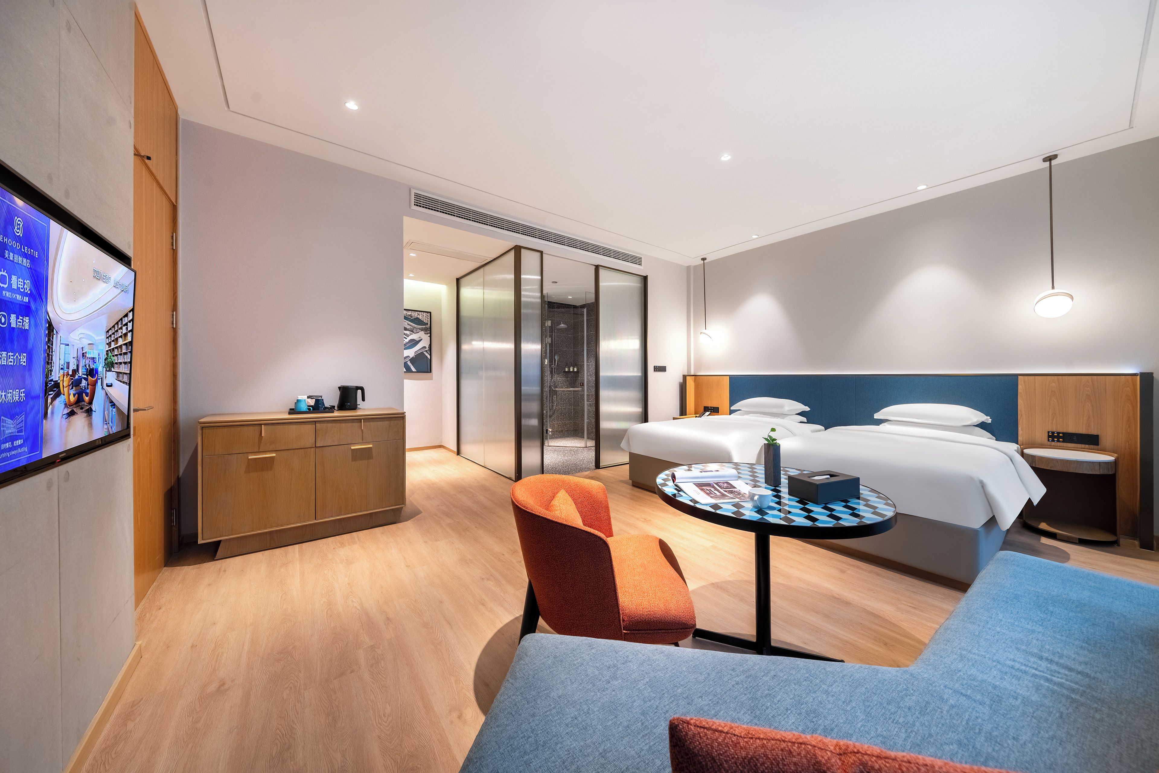 Una habitación de hotel moderna con cama, escritorio, silla y televisión en la pared.