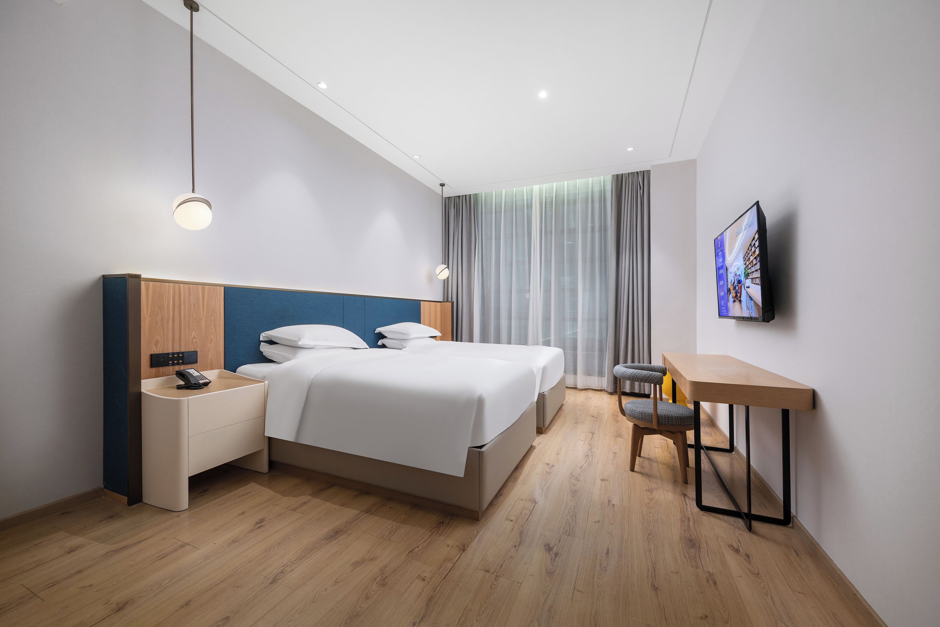 Una camera d'albergo moderna con un letto, un comodino, una lampada e una TV a parete.
