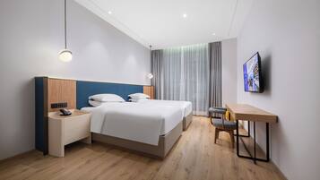 Una camera d'albergo moderna con un letto, un comodino, una lampada e una TV a parete.