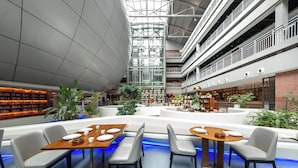 A spacious atrium with multiple levels, a central seating area with tables and chairs, and surrounding bookshelves. - Meihua Lizhi Hotel (Hangzhou)