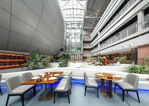 Un atrium espaiós amb diversos nivells, una zona central de seients amb taules i cadires, i prestatgeries al voltant.