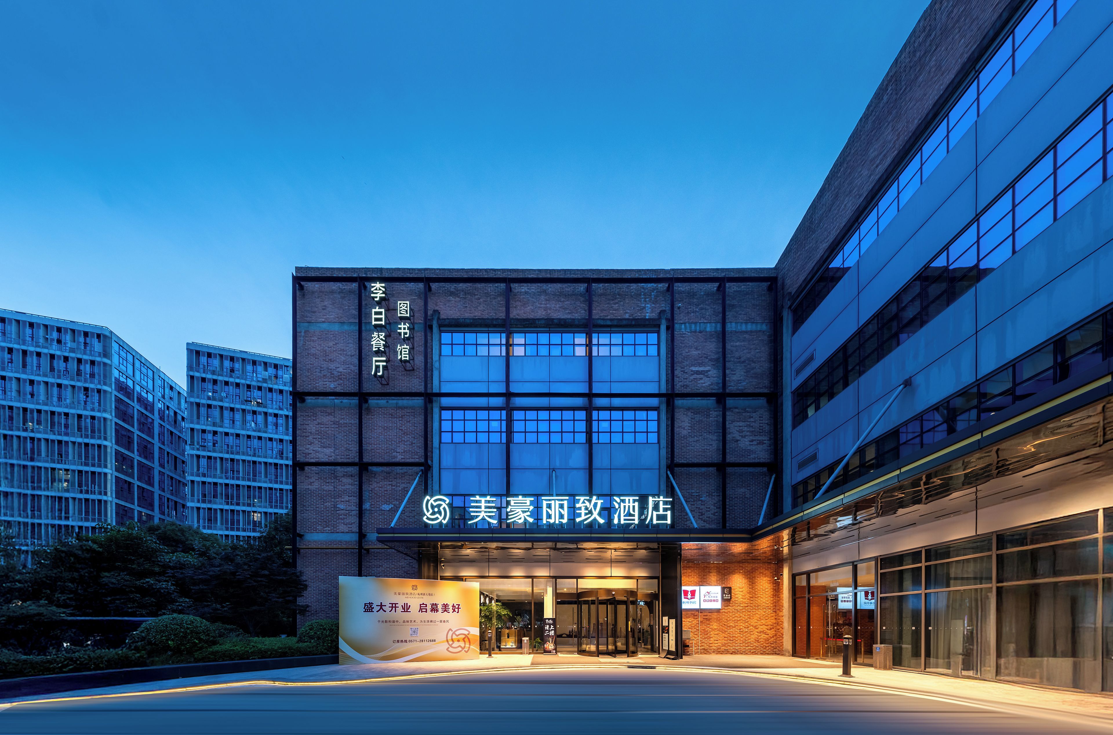 A hotel entrance with a modern facade, large glass windows, and a prominent sign.