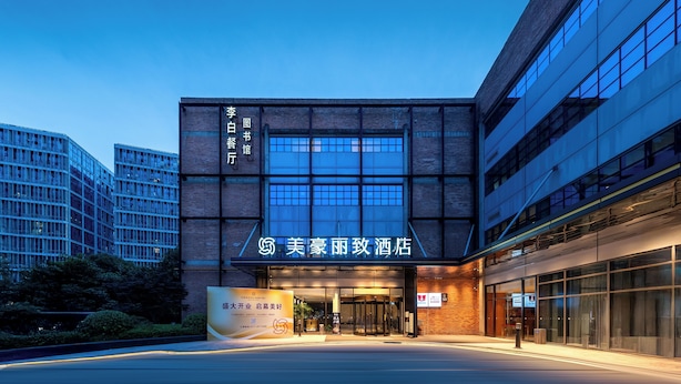 A hotel entrance with a modern facade, large glass windows, and a prominent sign. - Meihua Lizhi Hotel (Hangzhou)