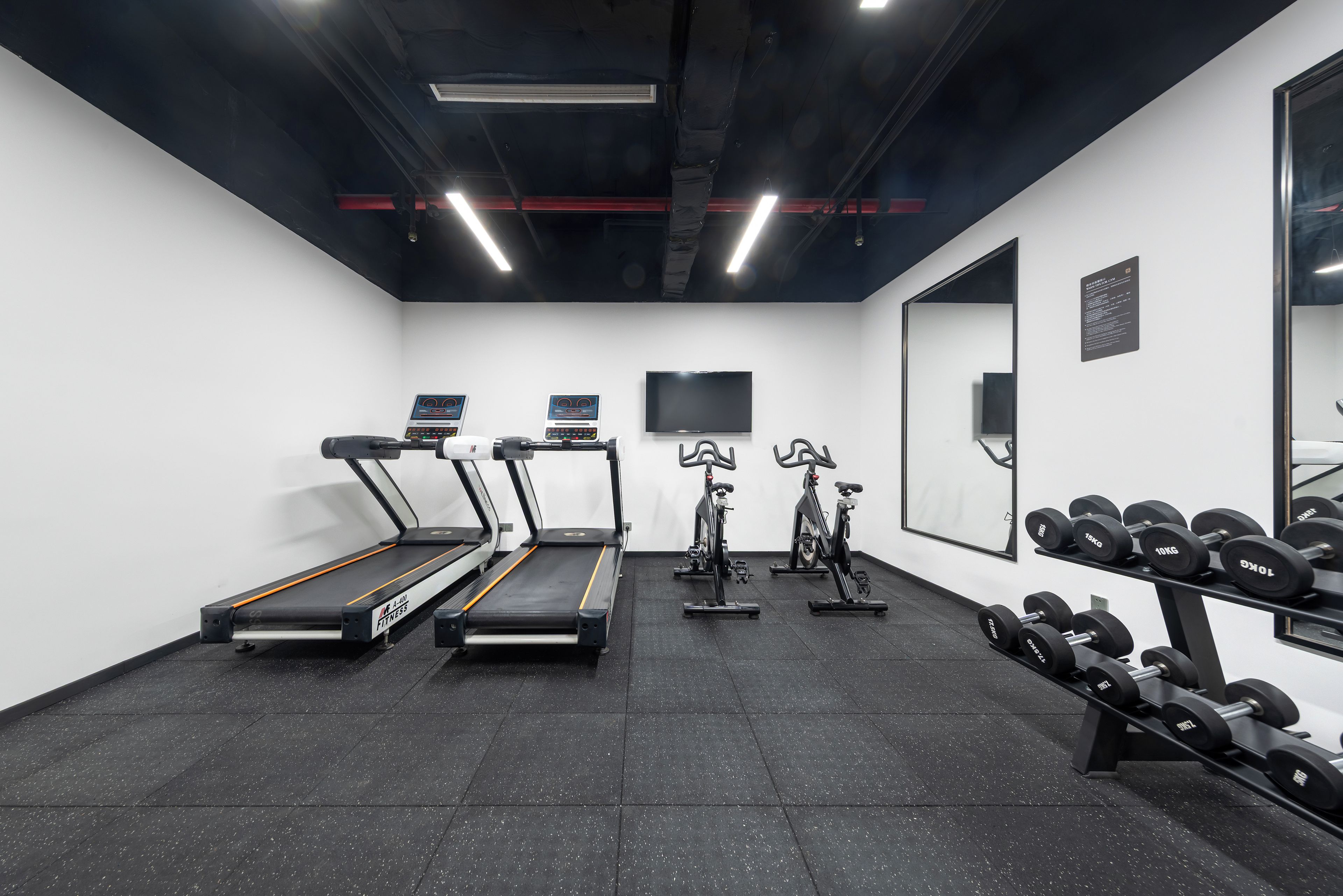 Una palestra con tapis roulant, cyclette e un rastrello di manubri.