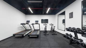 Una palestra con tapis roulant, cyclette e un rastrello di manubri.