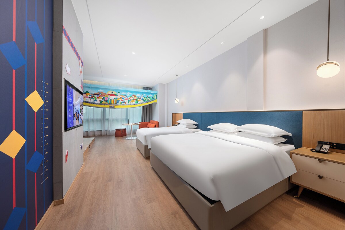 Una habitación de hotel con una cama grande, mesitas de noche, un escritorio y un televisor instalado en la pared.