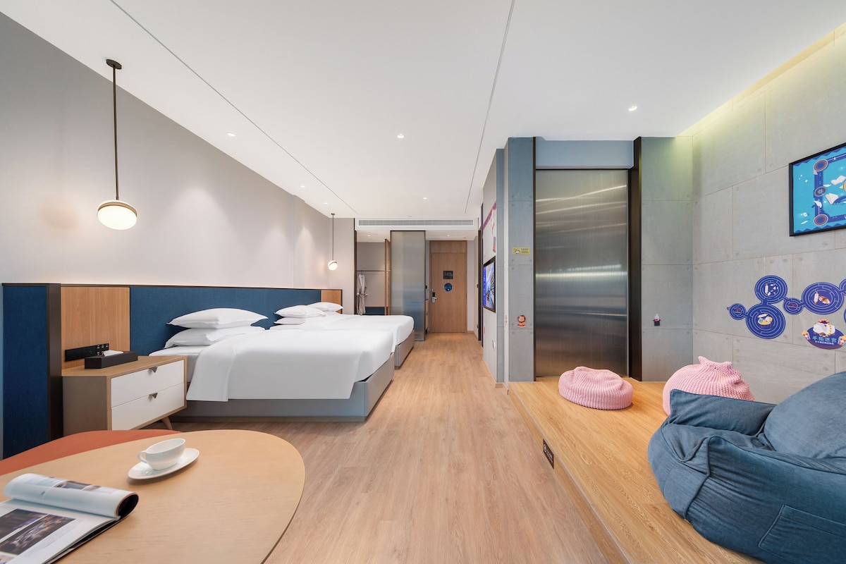 Habitació d'hotel moderna amb un llit, taules de nit, escriptori, cadira i una petita zona de seients.