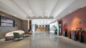 A modern hotel lobby with a reception desk, seating area, and a cityscape mural. - Meihua Lizhi Hotel (Hangzhou)