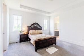 Un dormitorio con una cama grande, una mesita de noche, un aparador y una ventana.