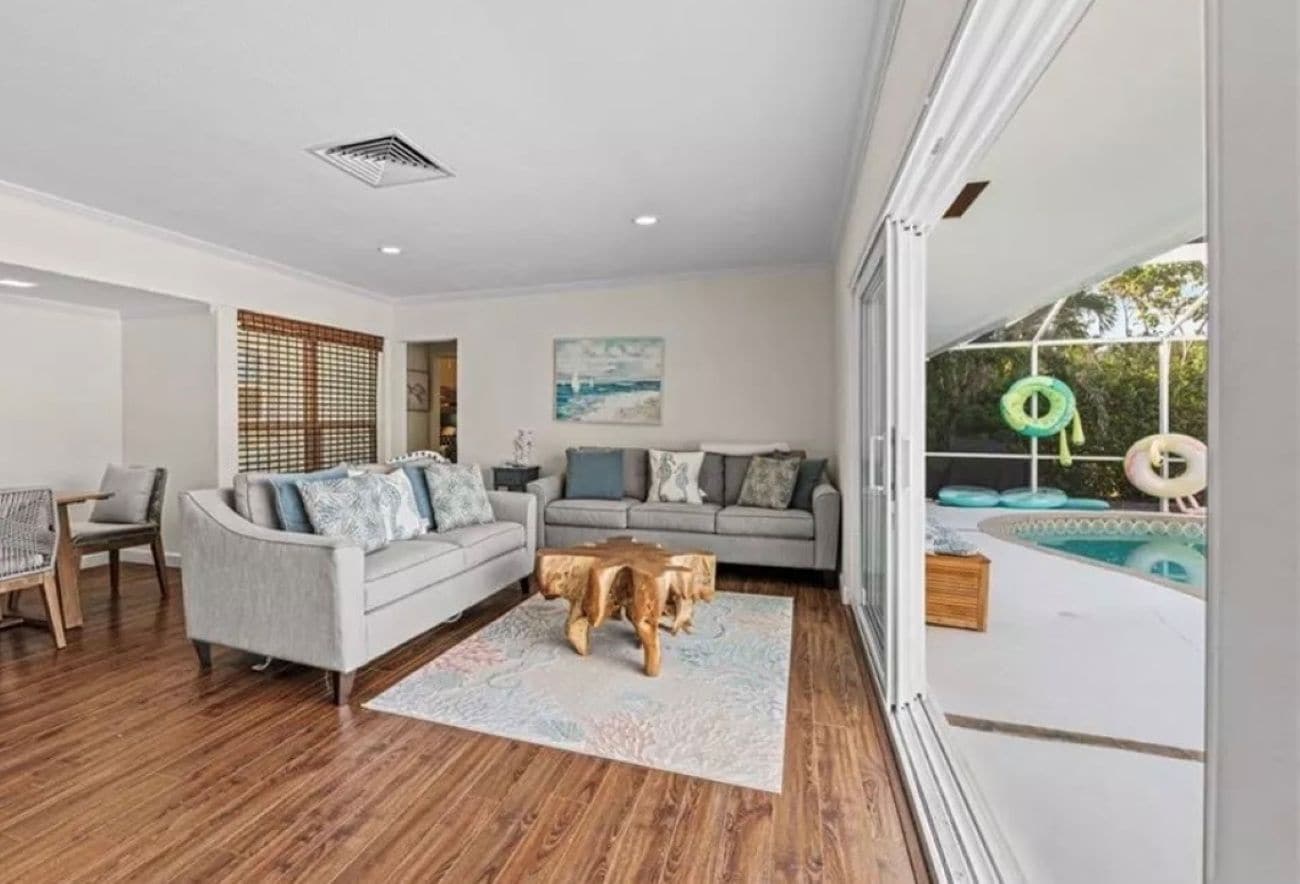 A living room with a sofa, coffee table, and a view of a swimming pool.