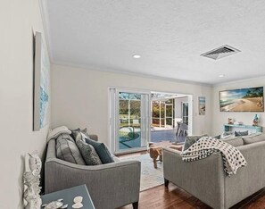 A living room with a grey sofa, a coffee table, and a painting on the wall. - Collier Cove - Marco Island Waterfront Retreat (Marco Island)