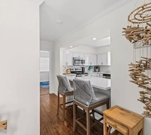 A modern kitchen with white cabinets, a central island, and two bar stools. - Collier Cove - Marco Island Waterfront Retreat (Marco Island)