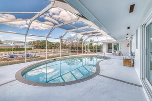 A covered swimming pool with a glass ceiling, a lounge area with chairs, and a view of the surrounding landscape. - Collier Cove - Marco Island Waterfront Retreat (Marco Island)