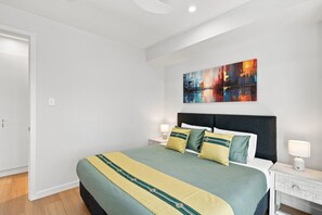 Una habitació d'hotel amb un llit gran, una tauleta de nit, una làmpada i un quadre a la paret.