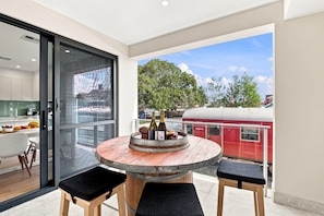 A modern kitchen with a dining area, a round wooden table with chairs, and a view of a red train outside.