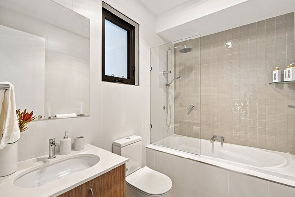 A modern bathroom with a glass-enclosed shower, a double sink vanity, and a toilet.