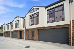 A modern residential building with a symmetrical facade, large windows, and a brick base.