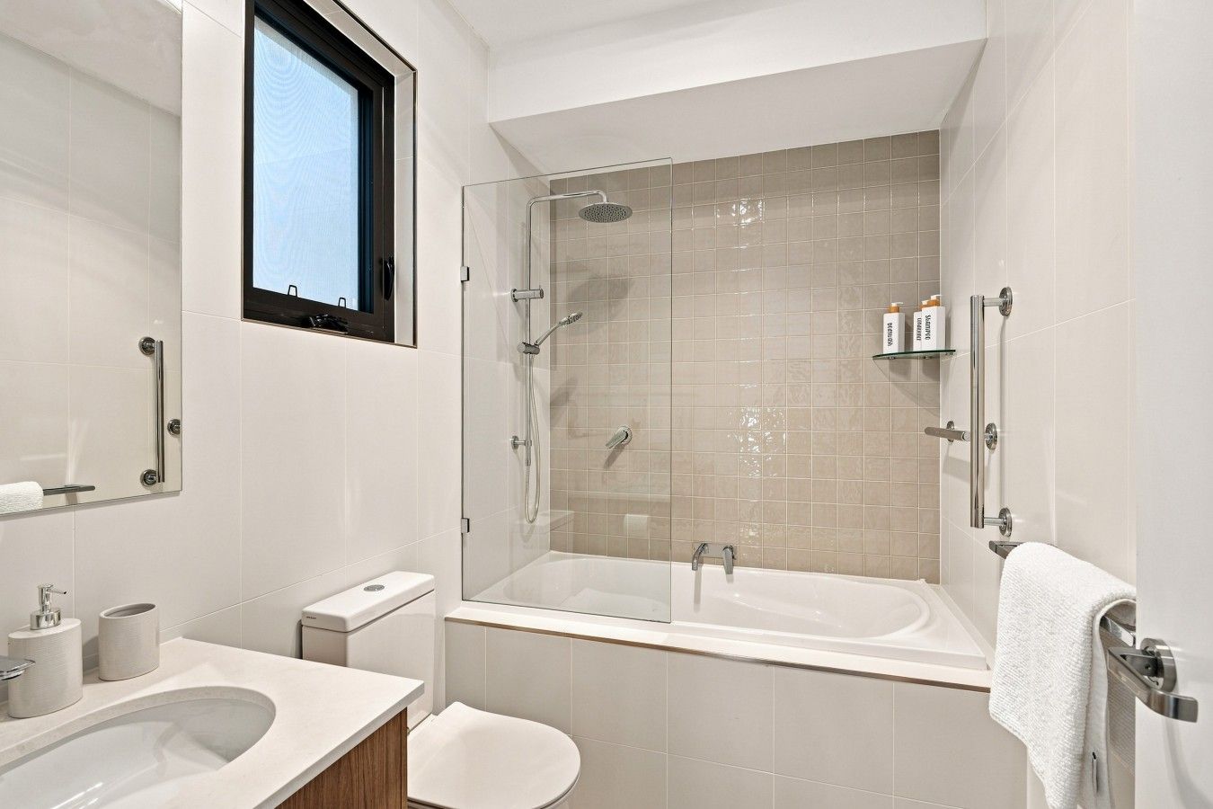 A modern bathroom with a glass-enclosed shower, a large bathtub, and a toilet.