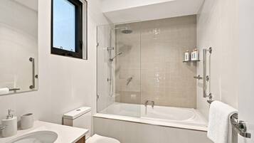 A modern bathroom with a glass-enclosed shower, a large bathtub, and a toilet.