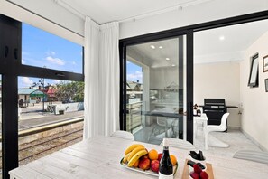 A dining area with a table set for two, a bottle of wine, and a fruit platter.