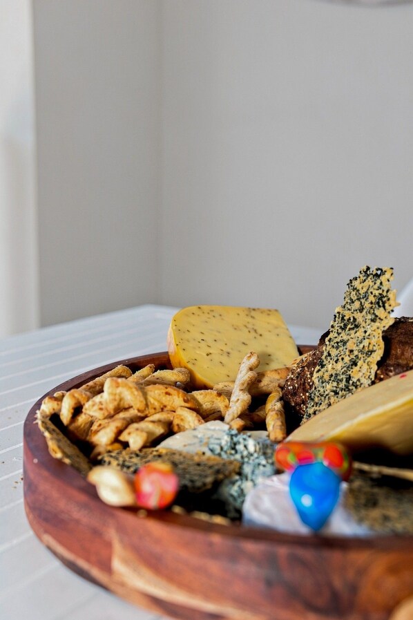 A wooden board with various cheeses and crackers.