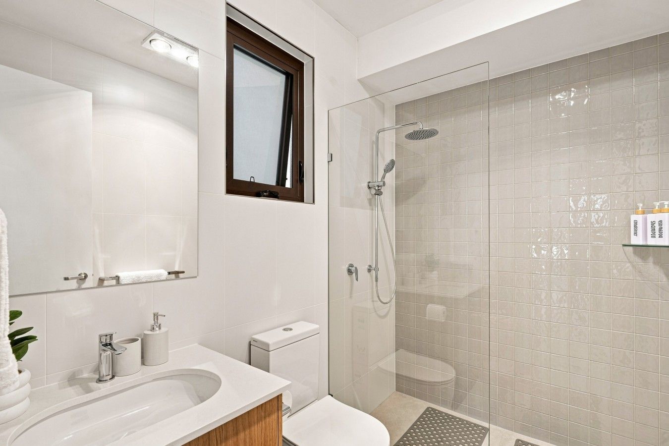 A modern bathroom with a glass-enclosed shower, a sink with a mirror, and a toilet.