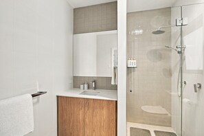 A modern bathroom with a glass-enclosed shower, a wooden vanity, and a large mirror.