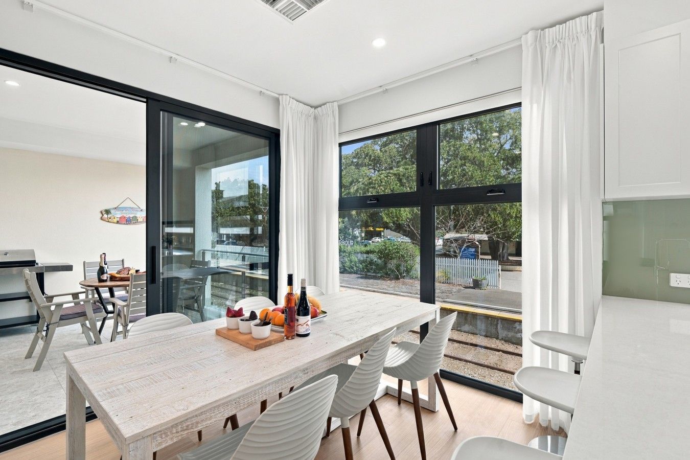 A modern dining area with a large table, chairs, and a view of the outdoors.