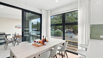 A modern dining area with a large table, chairs, and a view of the outdoors.