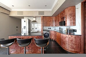 A modern kitchen with a central island, bar stools, stainless steel appliances, and copper-toned cabinetry. - Spacious Harbour Penthouse Two Bedroom Two Bathroom Harbour Mountain Views (Cape Town)
