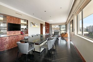 A modern dining area with a long table, chairs, and a television. - Spacious Harbour Penthouse Two Bedroom Two Bathroom Harbour Mountain Views (Cape Town)