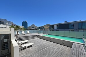 A rooftop pool area with lounge chairs and a view of a mountain and cityscape. - Spacious Harbour Penthouse Two Bedroom Two Bathroom Harbour Mountain Views (Cape Town)