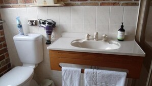 A bathroom with a toilet, sink, and a towel rack. - Emerald Tropical Palms B&B (Coffs Harbour)
