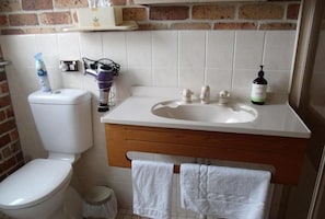 A bathroom with a toilet, sink, and a towel rack. - Emerald Tropical Palms B&B (Coffs Harbour)