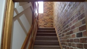 A staircase with a wooden handrail leading to a brick wall. - Emerald Tropical Palms B&B (Coffs Harbour)