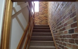 A staircase with a wooden handrail leading to a brick wall. - Emerald Tropical Palms B&B (Coffs Harbour)