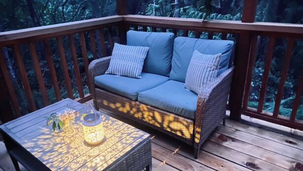 A wooden deck with a wicker sofa and a patterned table. - Forest Hideout - Peaceful Cabin Getaway in the woods (Duncan)